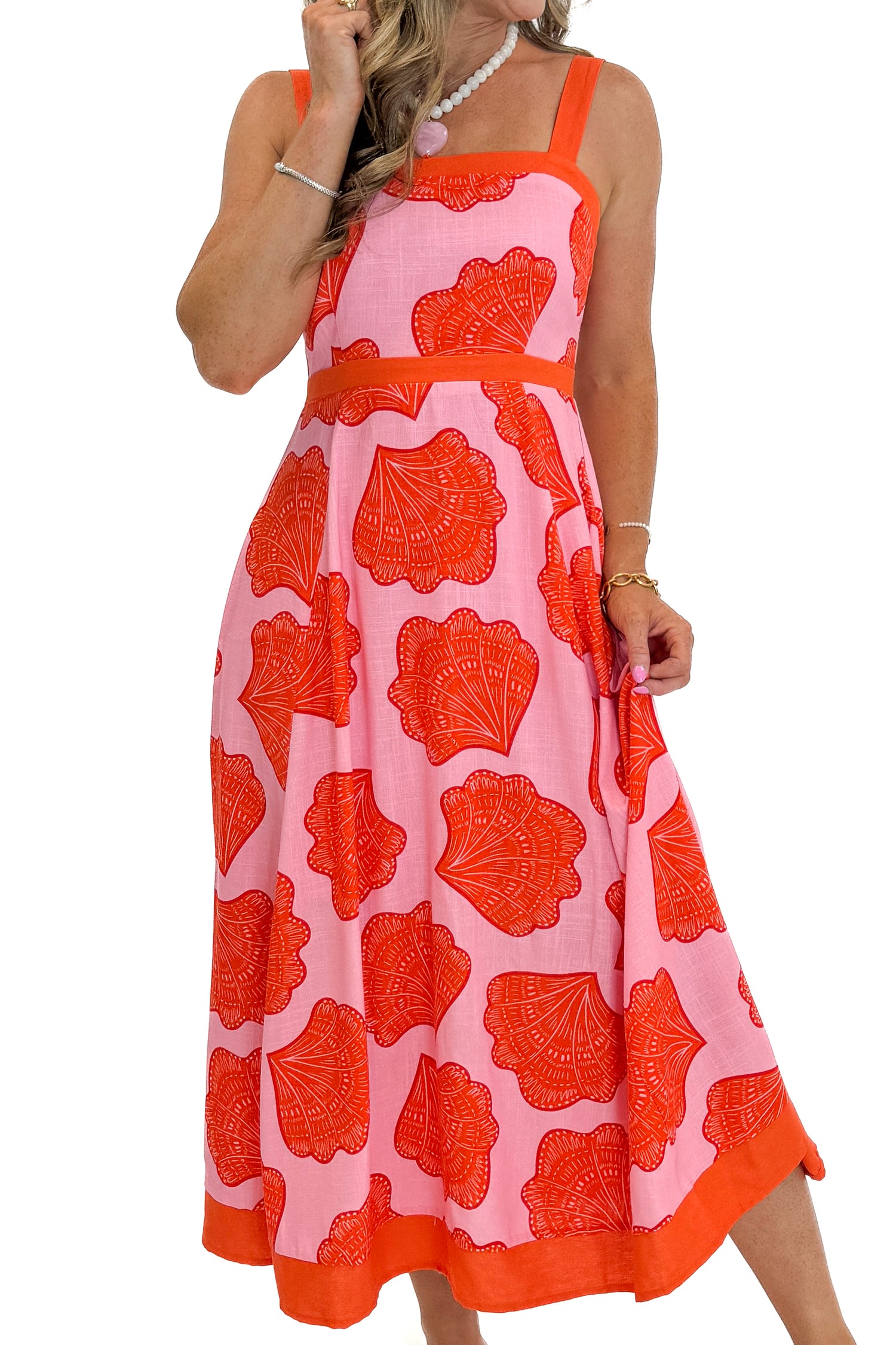 Front detail view of woman wearing Swagger Boutique’s Pink &amp; Orange Printed Midi Dress by Entro with sandals against white studio background.