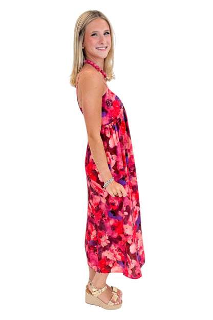 Side view of woman wearing Swagger Boutique’s Pink &amp; Red Floral Midi Dress with sandals against white studio background.