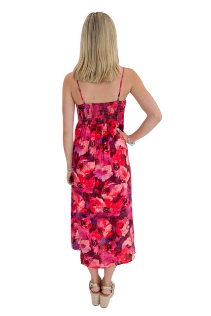 Back view of woman wearing Swagger Boutique’s Pink &amp; Red Floral Midi Dress with sandals against white studio background.
