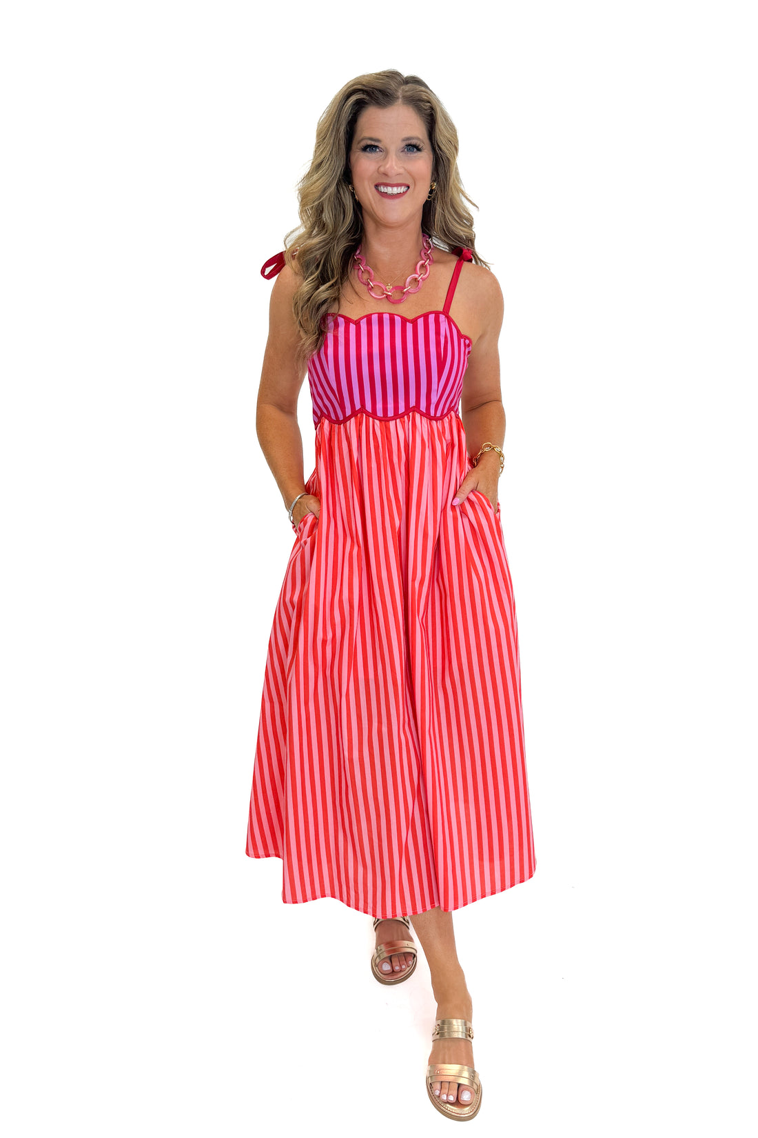 Front view of woman wearing Swagger Boutique’s Pink &amp; Red Striped Scalloped Midi Dress by Entro with sandals against white studio background.