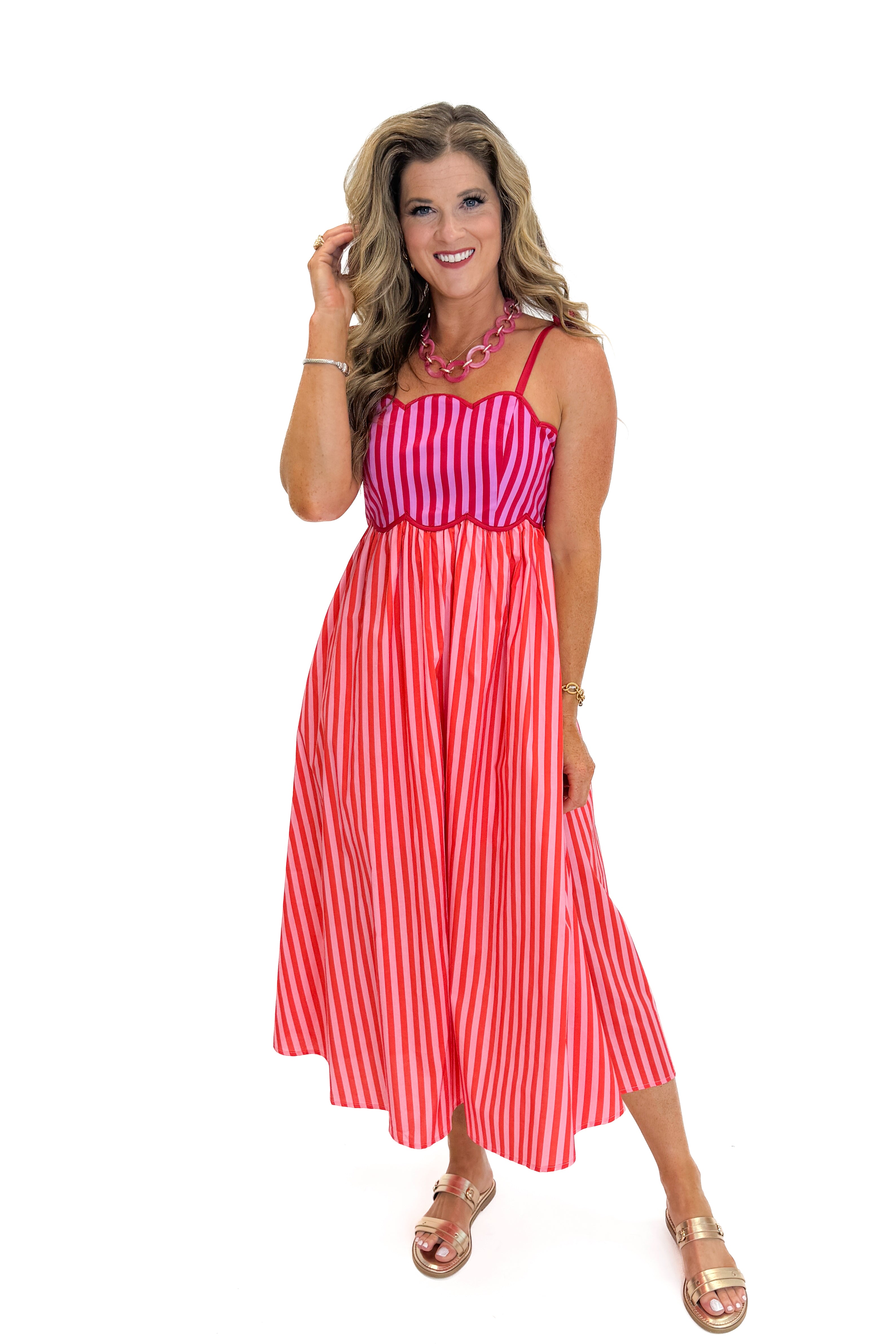 Front view of woman wearing Swagger Boutique’s Pink &amp; Red Striped Scalloped Midi Dress by Entro with sandals against white studio background.