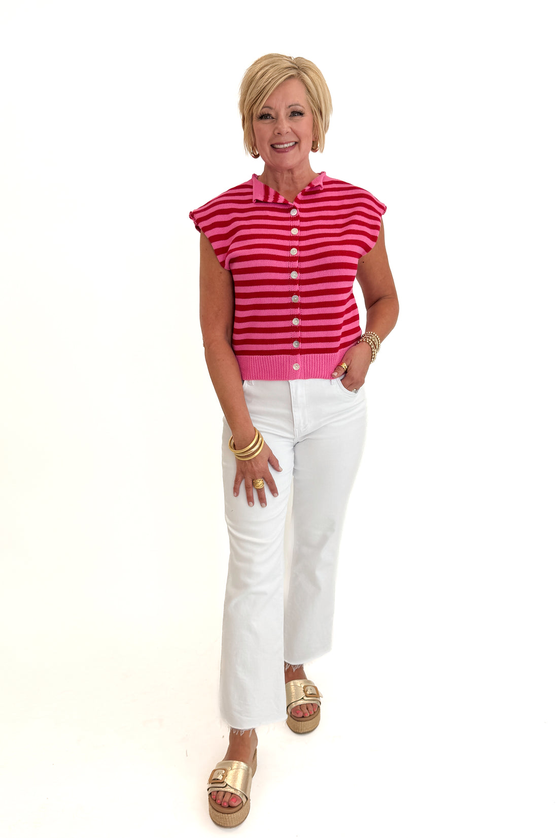 Front view of woman wearing Swagger Boutique’s Pink &amp; Red Striped Sleeveless Button Up Sweater by Entro with jeans against white studio background.