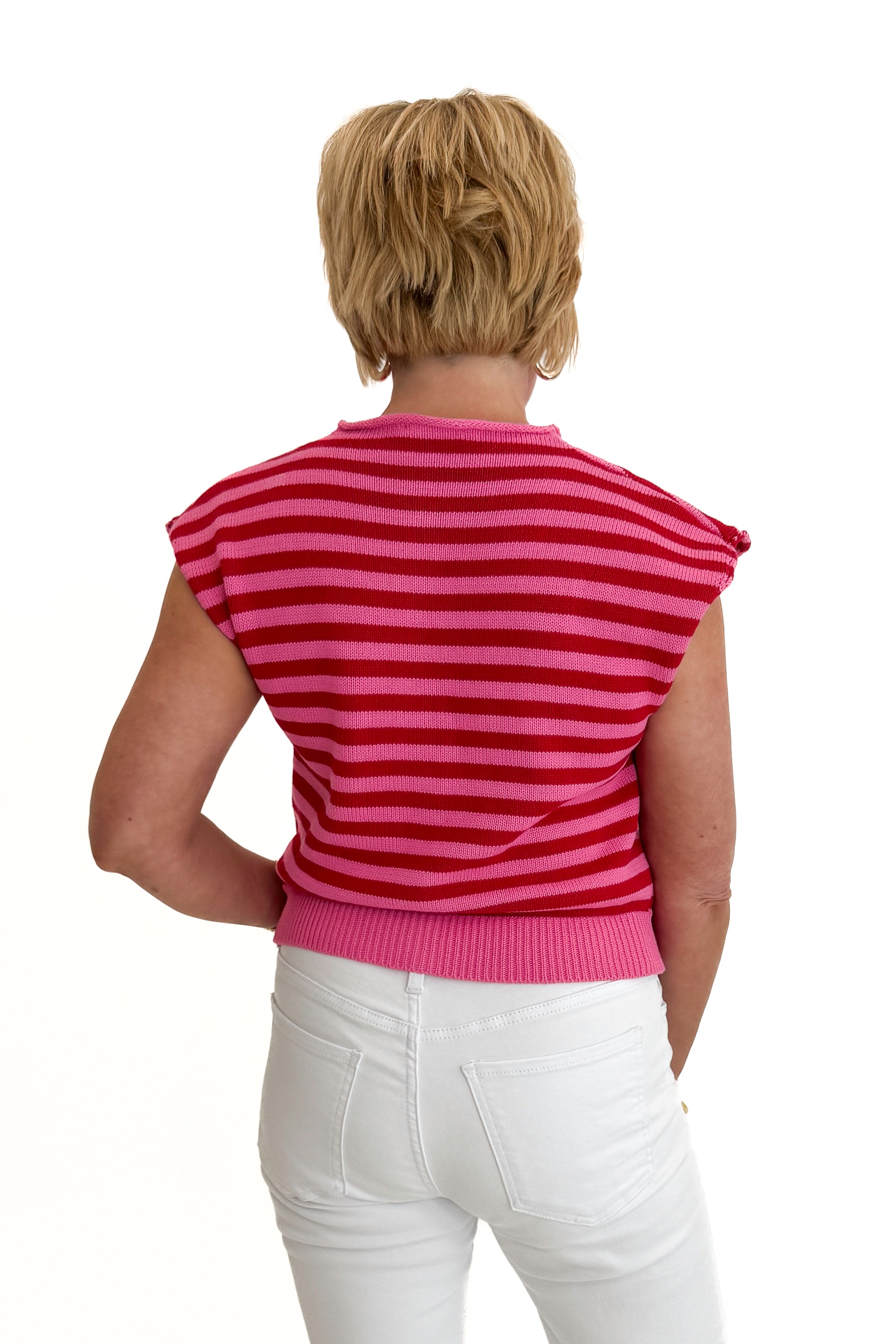 Back view of woman wearing Swagger Boutique’s Pink &amp; Red Striped Sleeveless Button Up Sweater by Entro with jeans against white studio background.