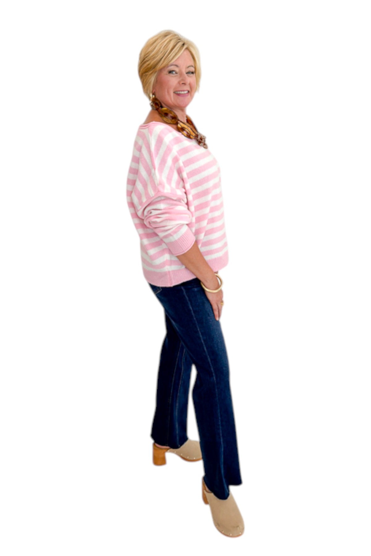 Side view of woman wearing Swagger Boutique’s Pink &amp; White Striped Sweater with jeans against white studio background.