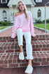 Front view of woman wearing Swagger Boutique’s Pink & White Striped Sweater with jeans sitting on a front porch step.