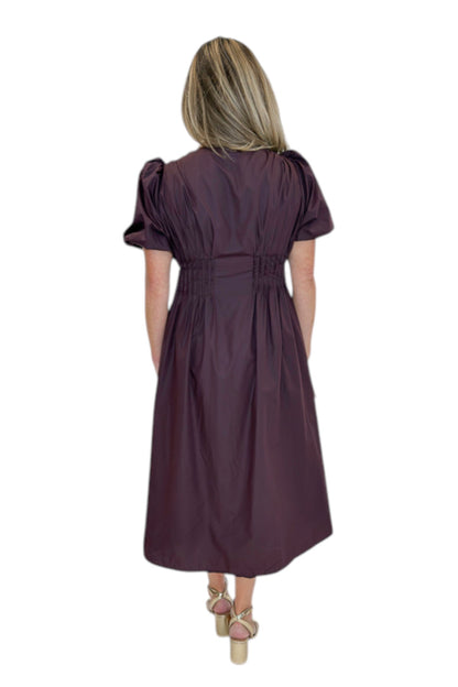 Back view of woman wearing Swagger Boutique’s Plum Pleated Waist Midi Dress by Entro with heels against white studio background.