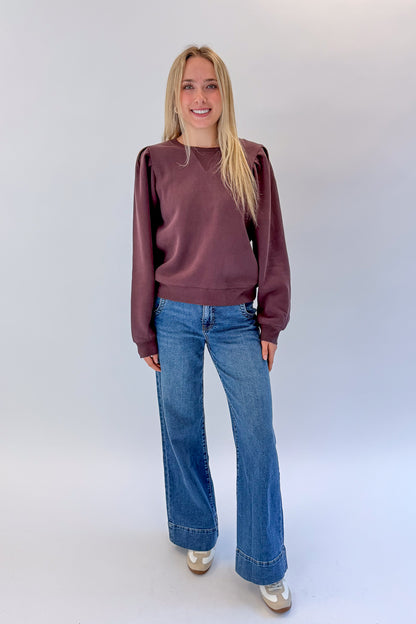 Front view of woman wearing Swagger Boutique’s Plum Puff Sleeve Sweatshirt with jeans against white studio background.