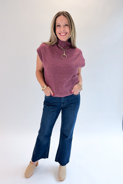 Front view of woman wearing Swagger Boutique’s Plum Sleeveless Mock Neck Sweater with jeans against white studio background.