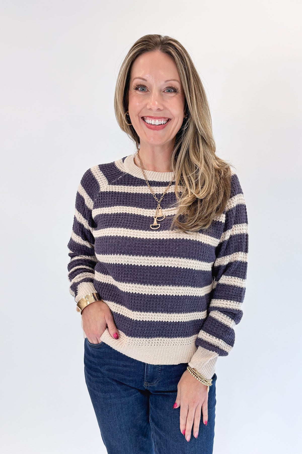 Front view of woman wearing Swagger Boutique’s Plum Striped Waffle Weave Sweater with jeans against white studio background.