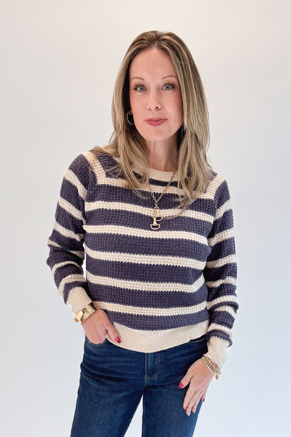 Front view of woman wearing Swagger Boutique’s Plum Striped Waffle Weave Sweater with jeans against white studio background.