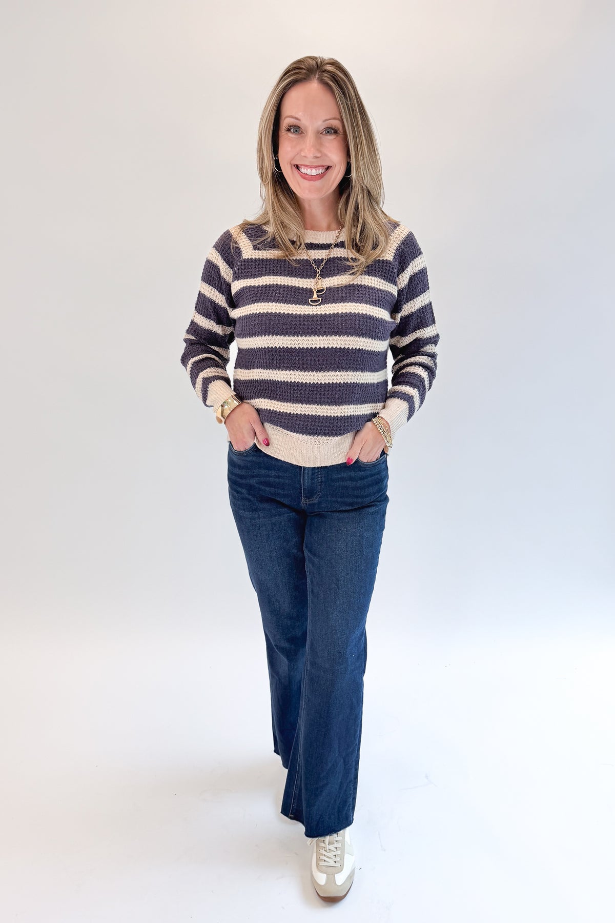 Front view of woman wearing Swagger Boutique’s Plum Striped Waffle Weave Sweater with jeans against white studio background.