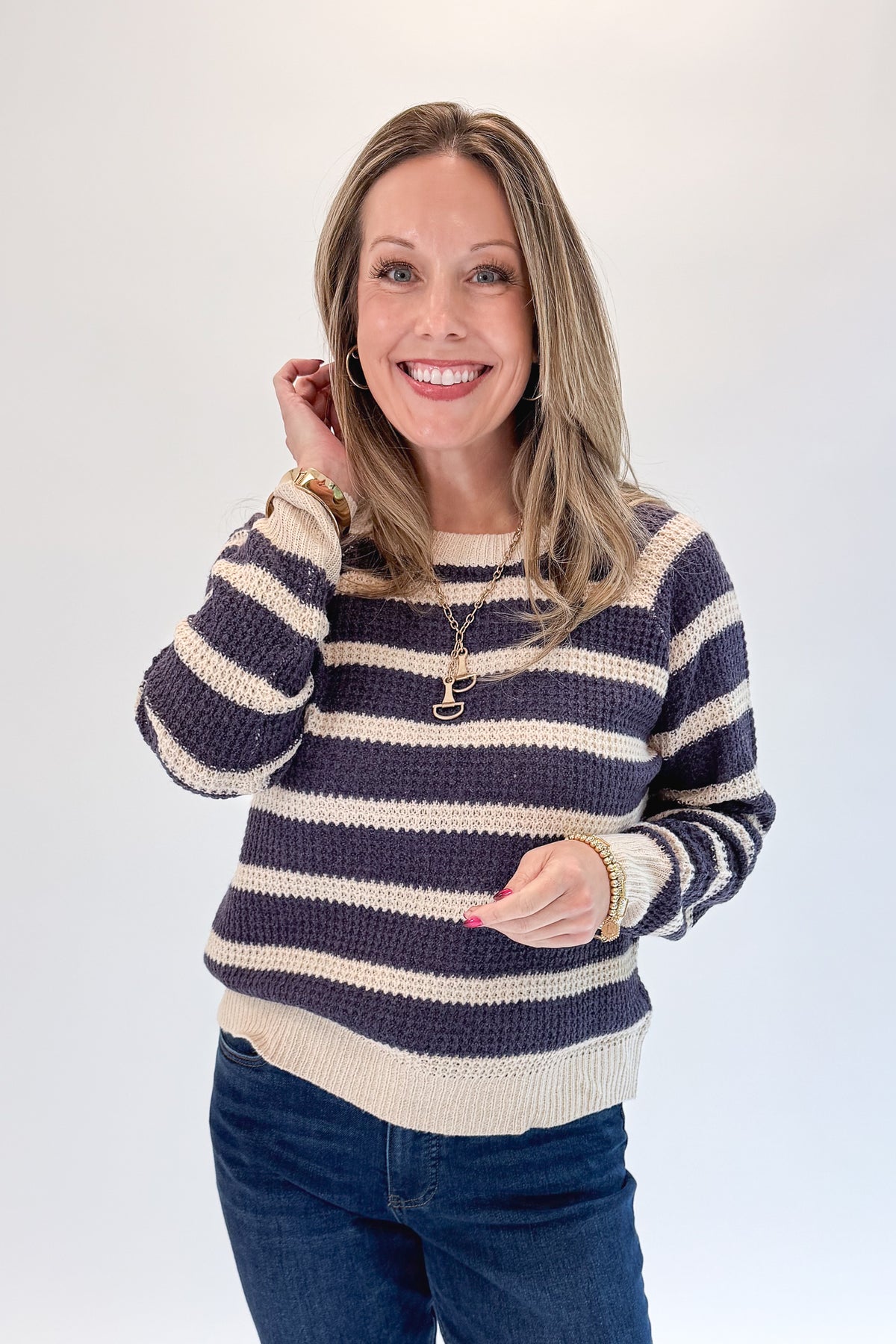 Front view of woman wearing Swagger Boutique’s Plum Striped Waffle Weave Sweater with jeans against white studio background.