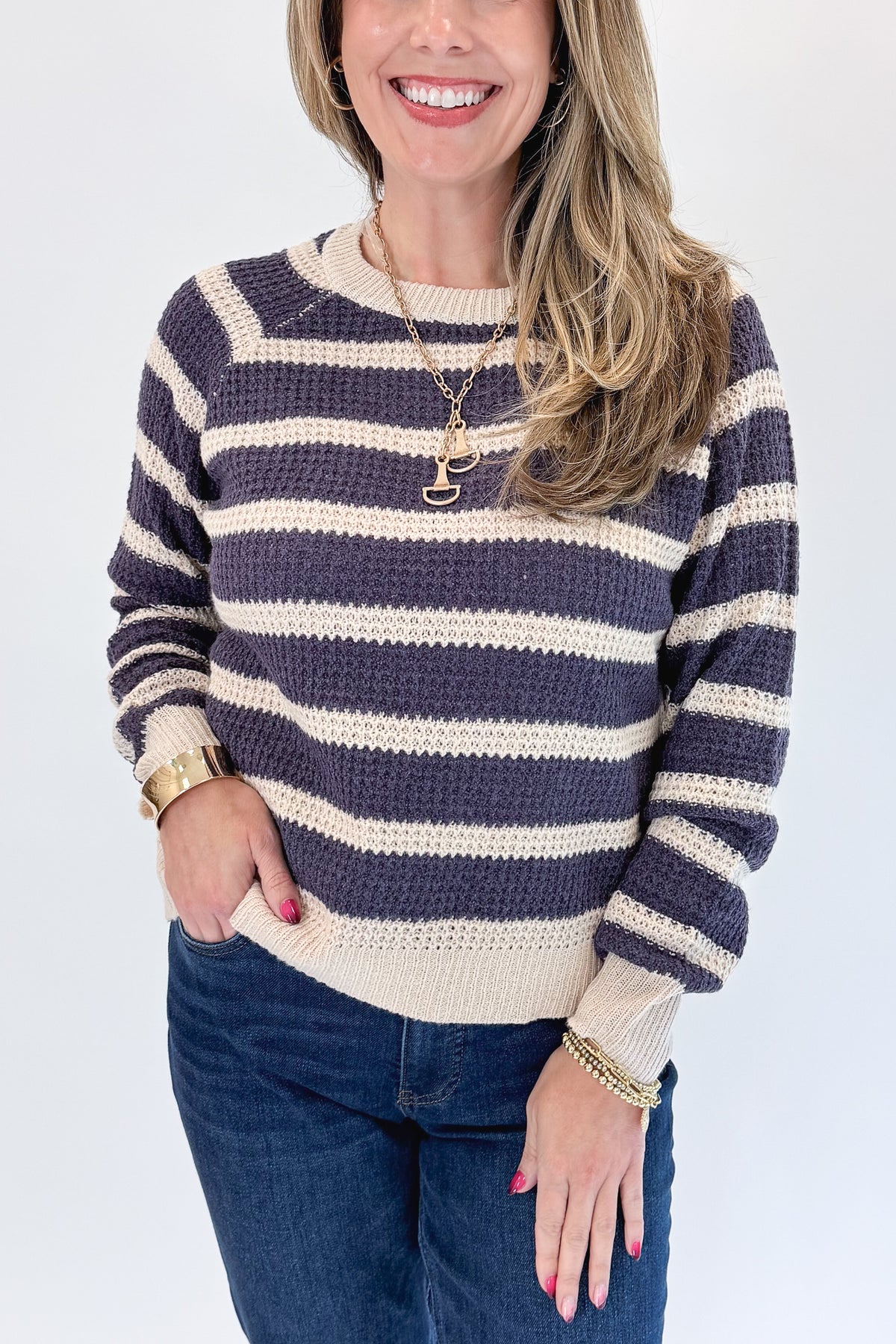 Front detail view of woman wearing Swagger Boutique’s Plum Striped Waffle Weave Sweater with jeans against white studio background.