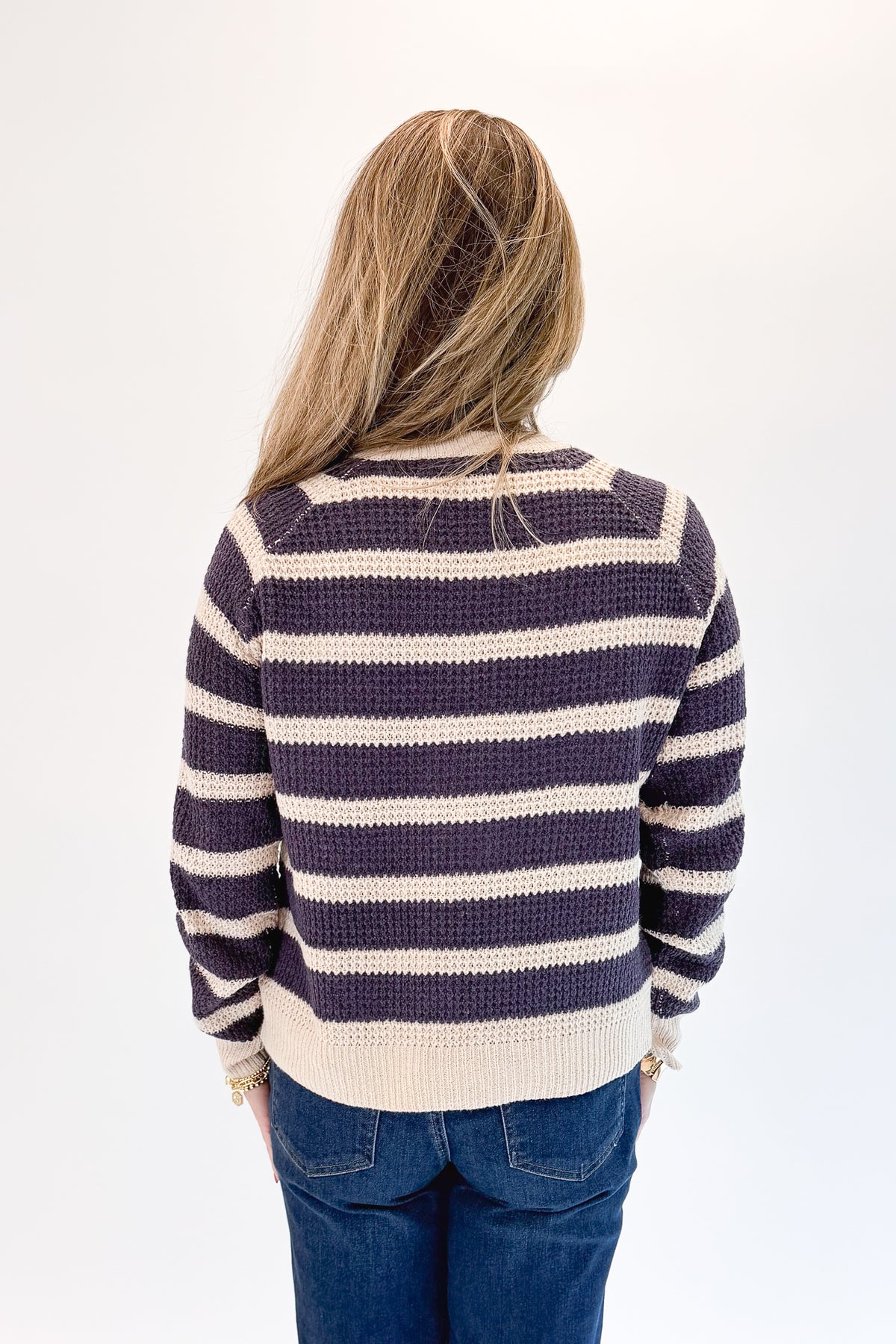 Back view of woman wearing Swagger Boutique’s Plum Striped Waffle Weave Sweater with jeans against white studio background.