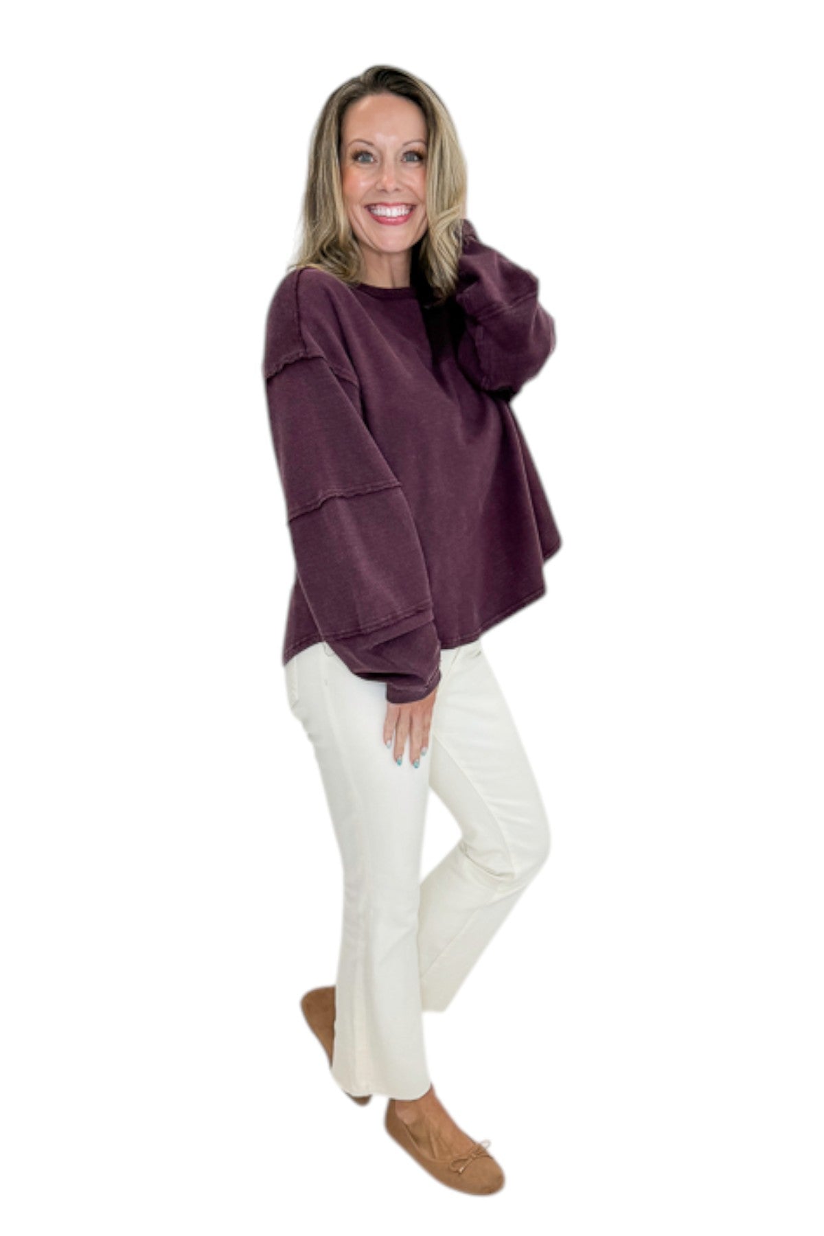 Side view of woman wearing Swagger Boutique’s Plum Textured Sweatshirt with jeans against white studio background.