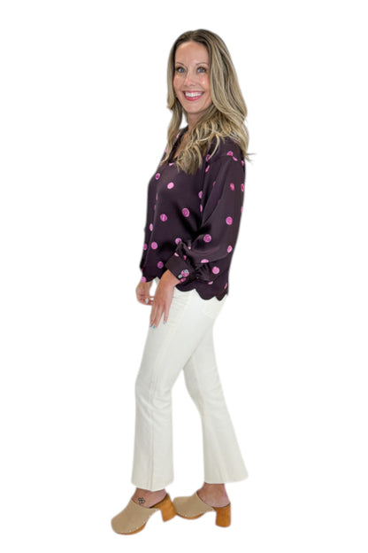 Side view of woman wearing Swagger Boutique’s Plum &amp; Pink Polka Dot 3/4 Sleeve Top by Entro with jeans against white studio background.