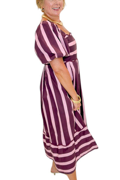 Side view of woman wearing Swagger Boutique’s Plum &amp; Pink Striped Midi Dress by Entro with sandals against white studio background.