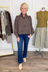 Front view of woman wearing Swagger Boutique’s Polka Dot Button Up Top with jeans with clothing hanging in the background.