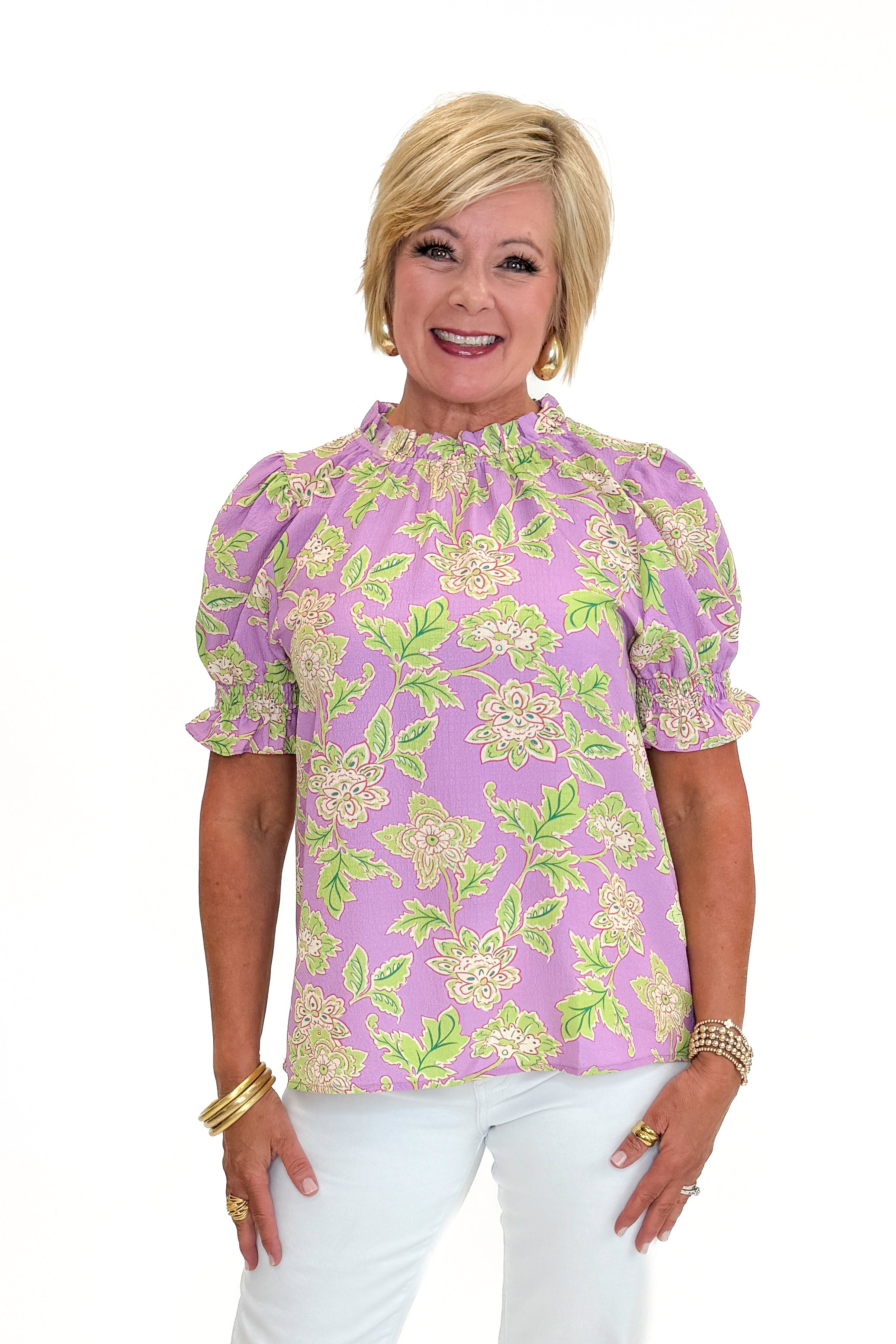 Front view of woman wearing Swagger Boutique’s Purple Floral Short Sleeve Ruffle Top with jeans against white studio background.