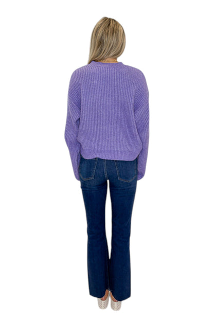 Back view of woman wearing Swagger Boutique’s Purple Ribbed sweater with jeans against white studio background.