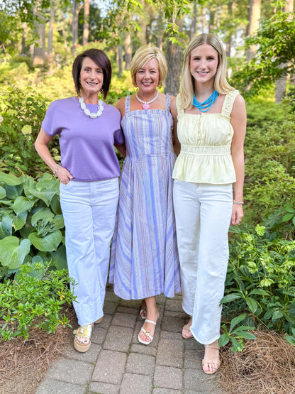 Front view of woman wearing Swagger Boutique’s Purple Short Sleeve Banded Top with jeans and two other women standing outside.