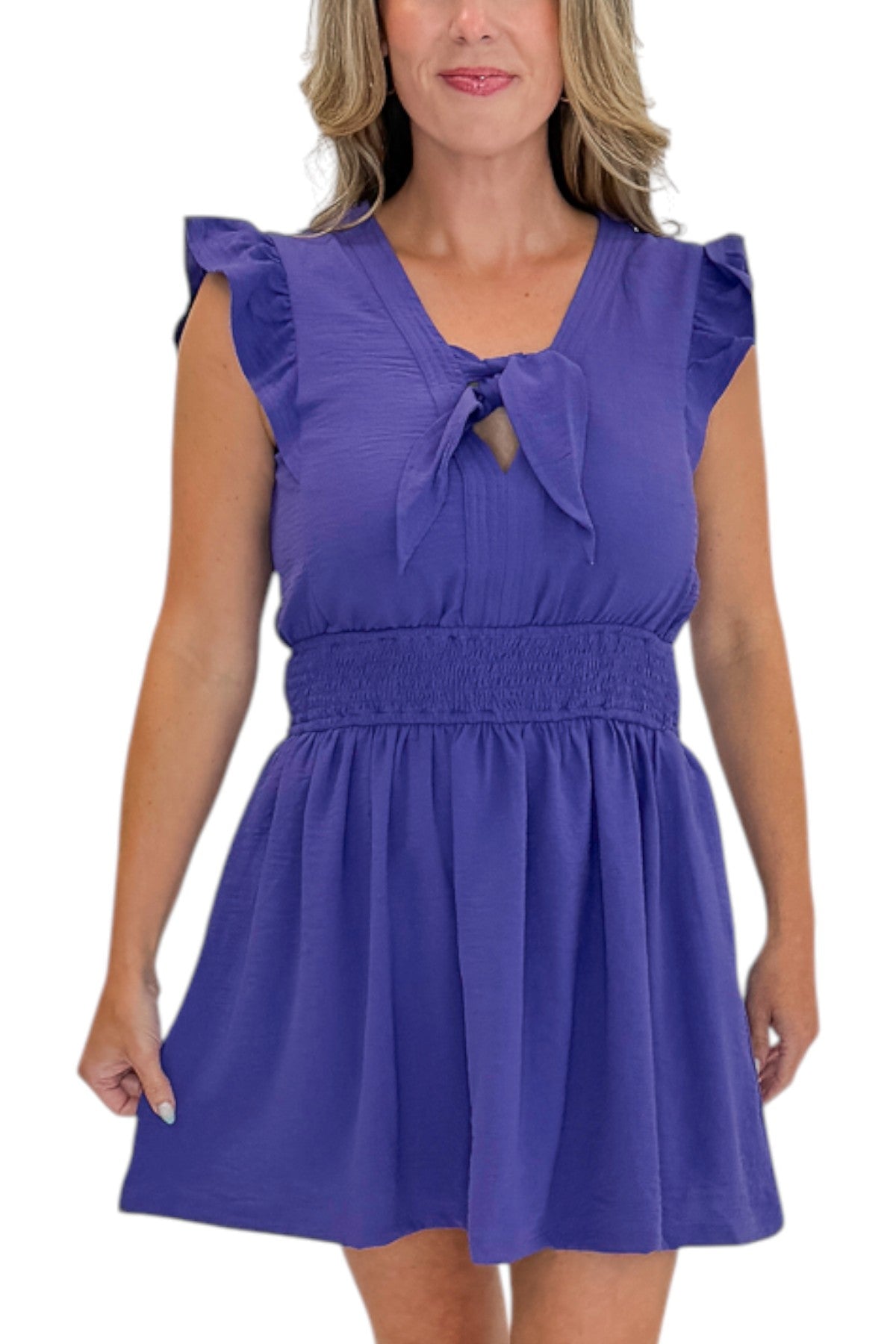 Front detail view of woman wearing Swagger Boutique’s Purple Tie Detail Smocked Waist Dress with sandals against white studio background.