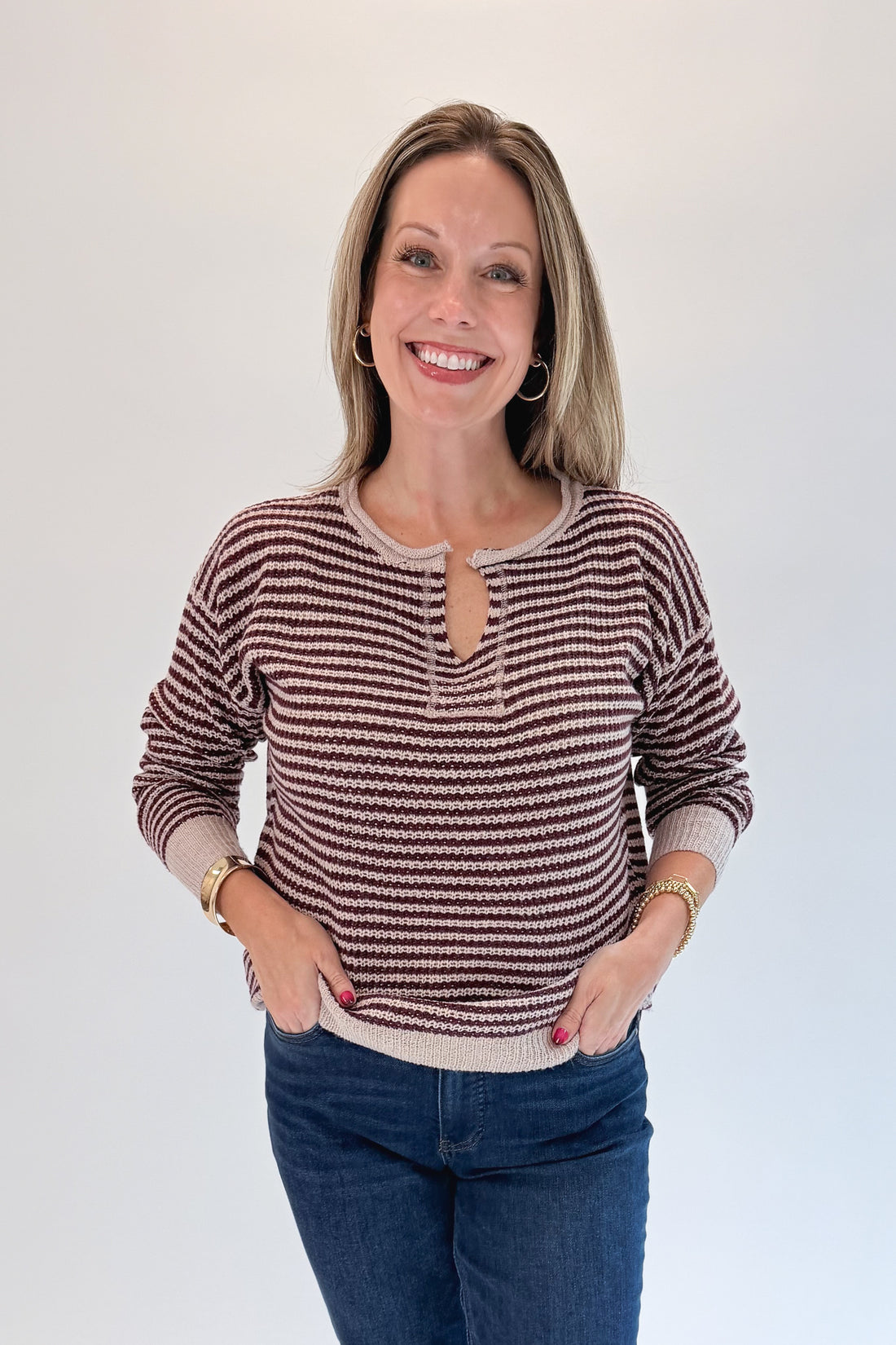 Front view of woman wearing Swagger Boutique’s Purple &amp; Beige Striped Knit Sweater with jeans against white studio background.