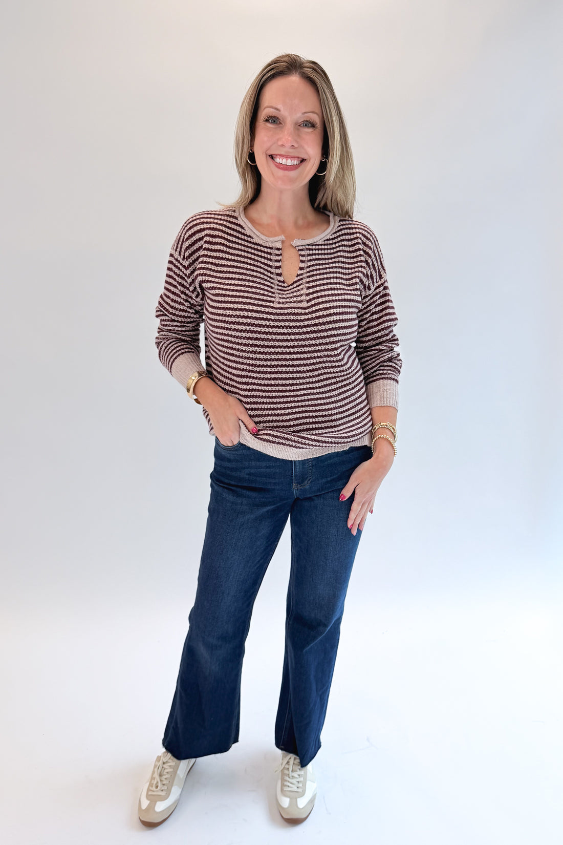 Front view of woman wearing Swagger Boutique’s Purple &amp; Beige Striped Knit Sweater with jeans against white studio background.