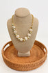 Necklace on a beige bust with a woven brown base against a white background