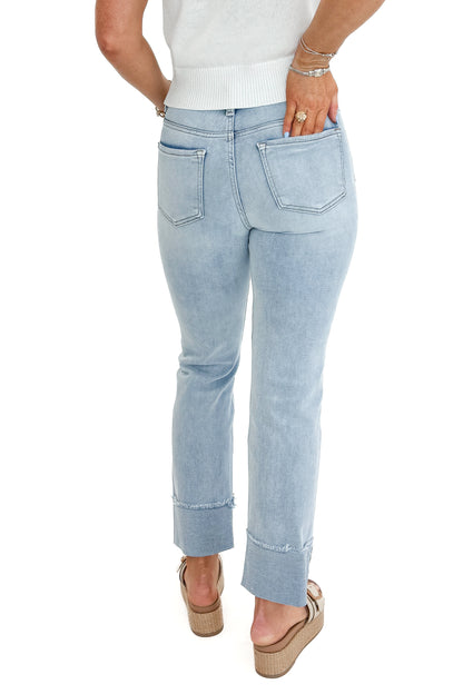 Back view of woman wearing sweater with Light Wash Relaxed Straight Jeans by Risen against white studio background.