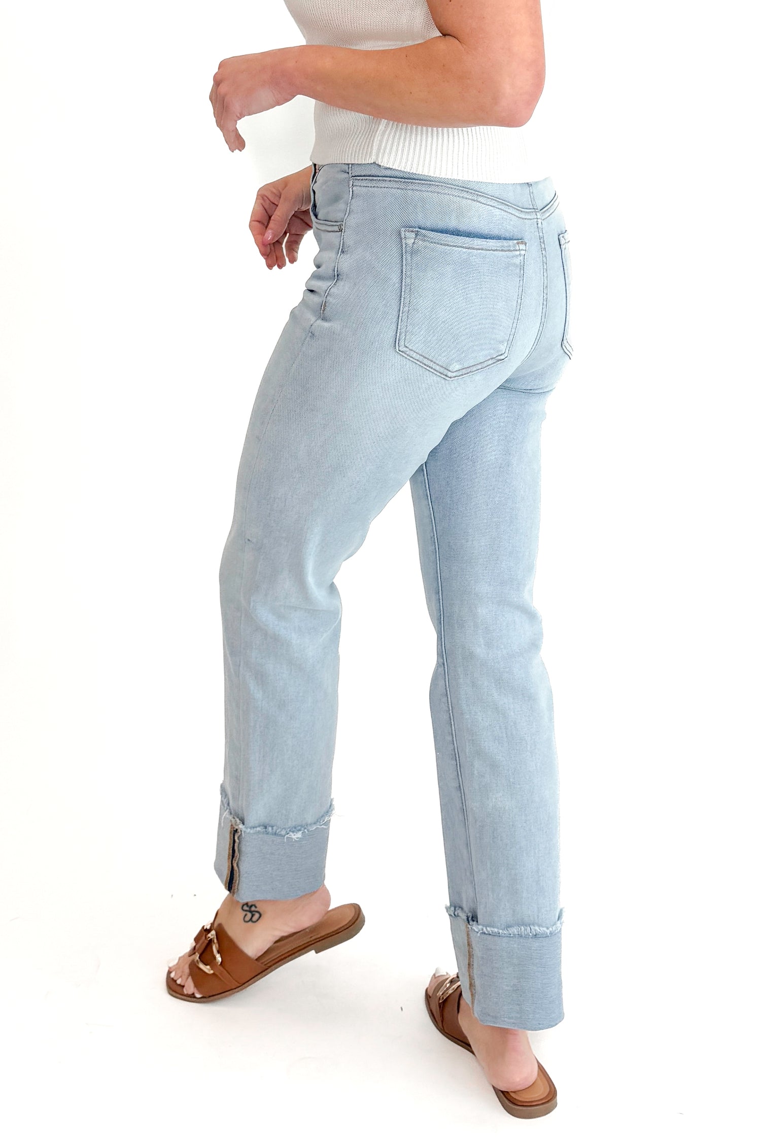 Side view of woman wearing sweater with Light Wash Relaxed Straight Jeans by Risen against white studio background.