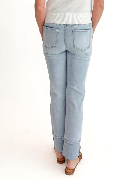 Back view of woman wearing sweater with Light Wash Relaxed Straight Jeans by Risen against white studio background.