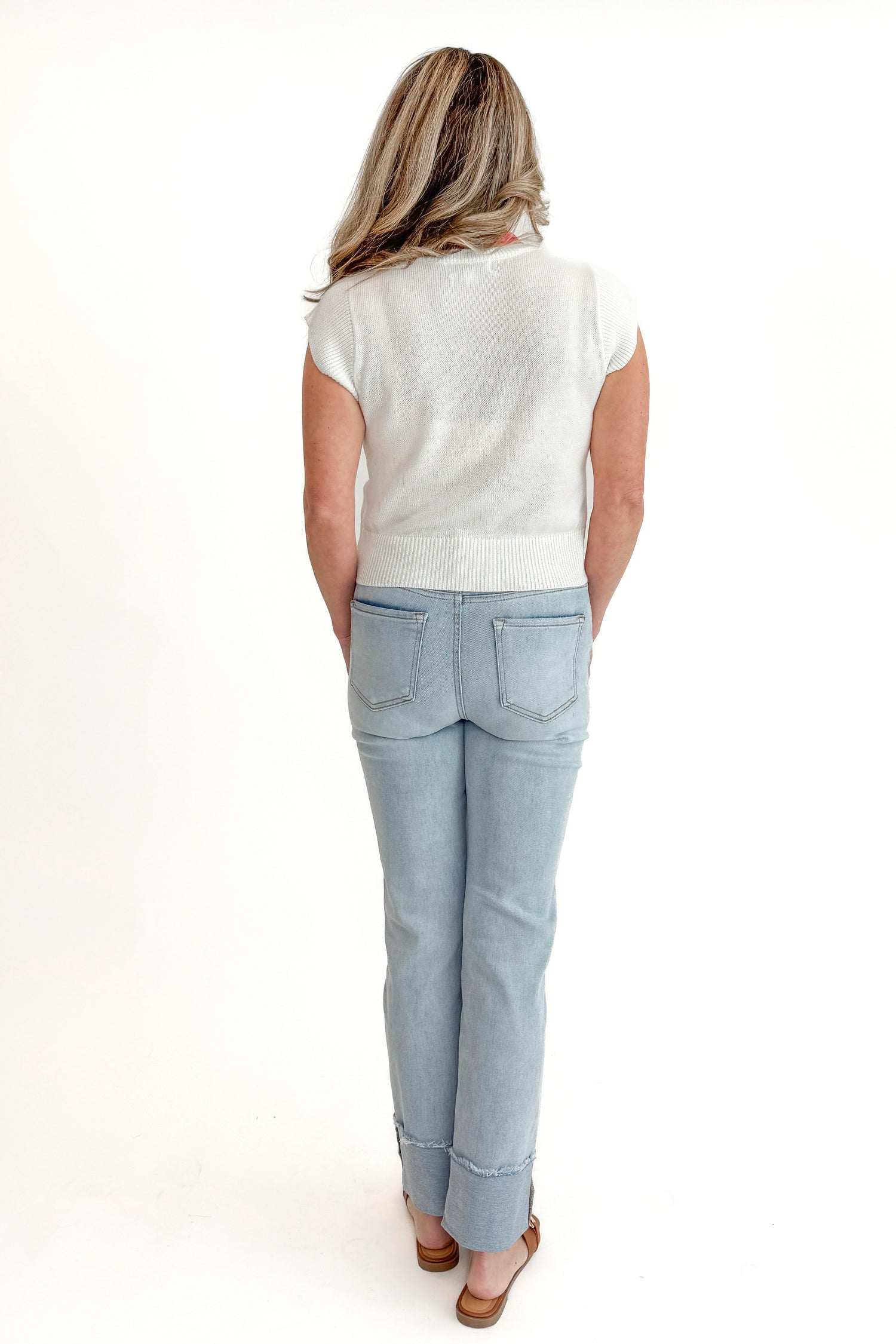 Back view of woman wearing sweater with Light Wash Relaxed Straight Jeans by Risen against white studio background.