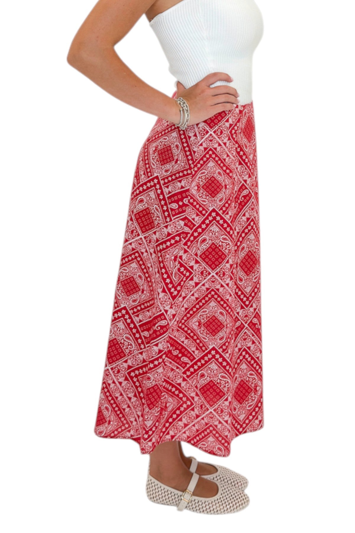 Side view of woman wearing Swagger Boutique’s Red Bandana Print Midi Skirt with white top against white studio background.