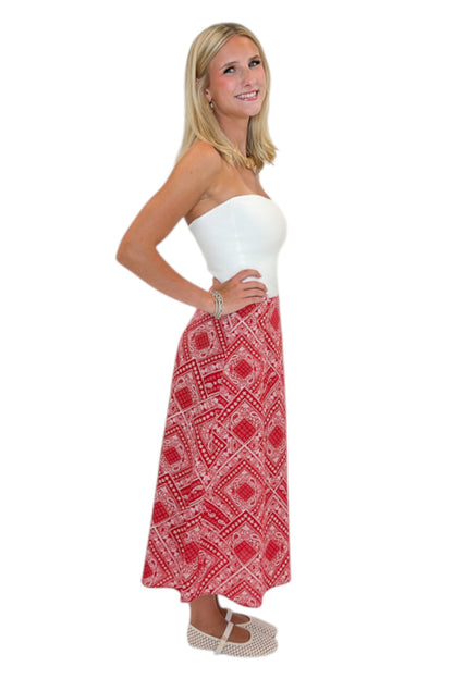 Side view of woman wearing Swagger Boutique’s Red Bandana Print Midi Skirt with white top against white studio background.