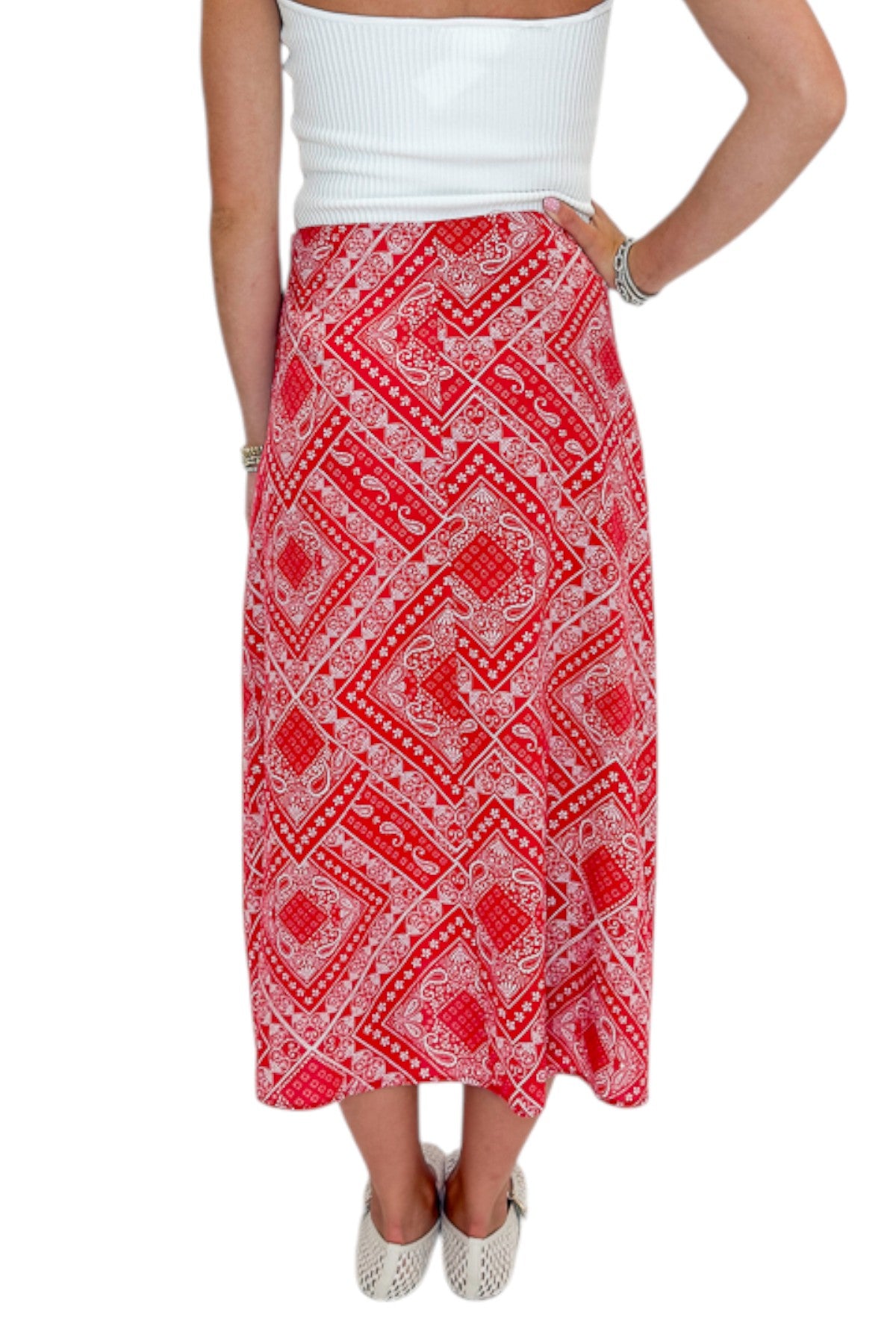 Back view of woman wearing Swagger Boutique’s Red Bandana Print Midi Skirt with white top against white studio background.