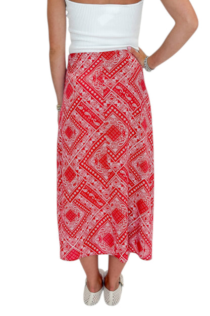 Back view of woman wearing Swagger Boutique’s Red Bandana Print Midi Skirt with white top against white studio background.