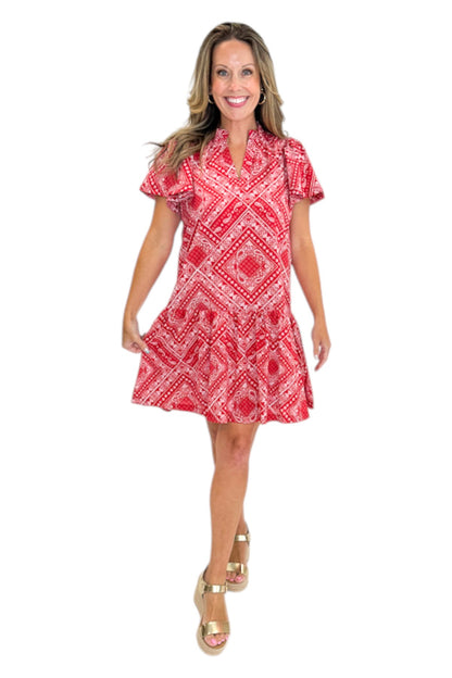 Front view of woman wearing Swagger Boutique’s Red Bandana Print Mini Dress with sandals against white studio background.