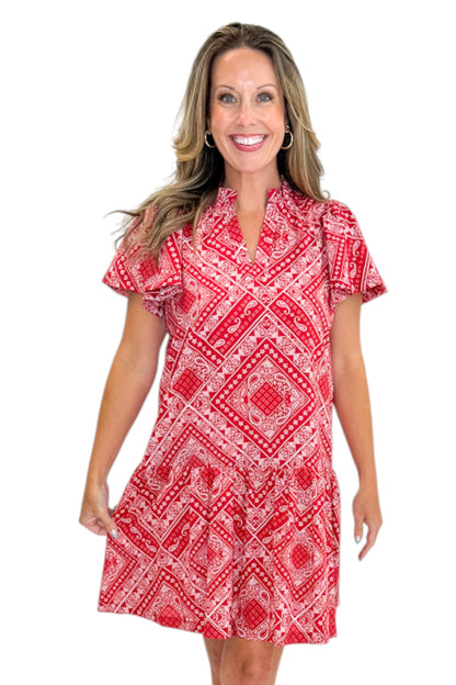 Front view of woman wearing Swagger Boutique’s Red Bandana Print Mini Dress with sandals against white studio background.