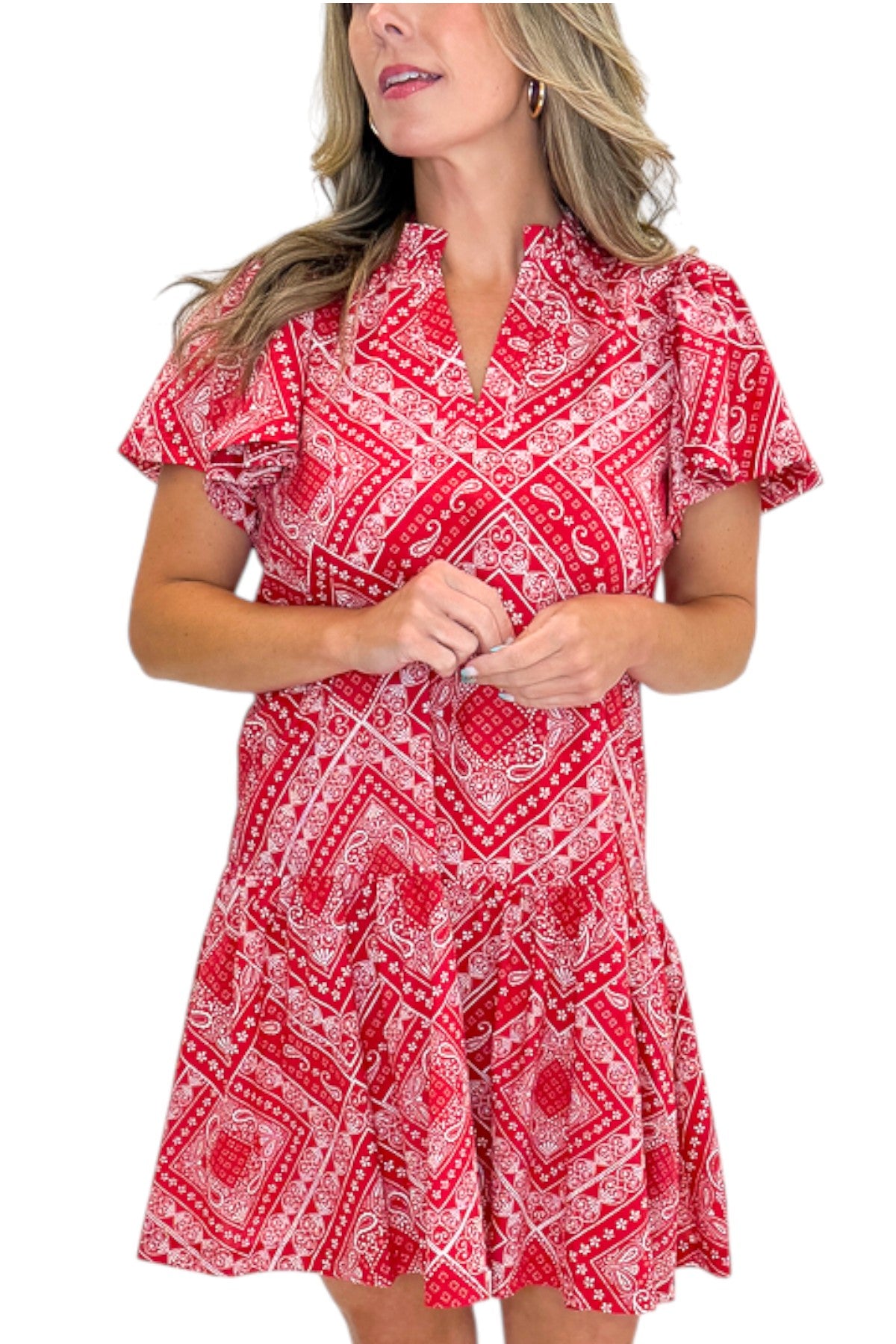 Front details view of woman wearing Swagger Boutique’s Red Bandana Print Mini Dress with sandals against white studio background.