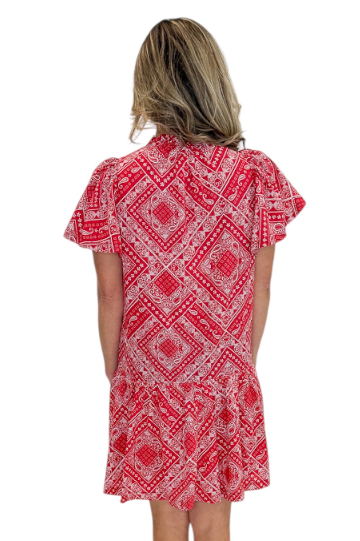 Back view of woman wearing Swagger Boutique’s Red Bandana Print Mini Dress with sandals against white studio background.