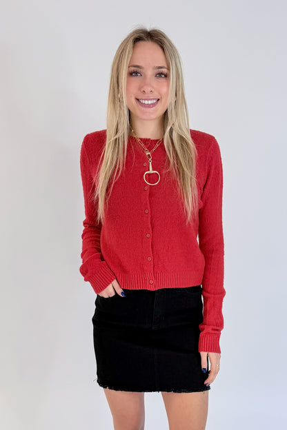 Front view of woman wearing Swagger Boutique’s Red Button Up Cardigan with Black Denim Mini Skirt by Just Black Denim against white studio background.