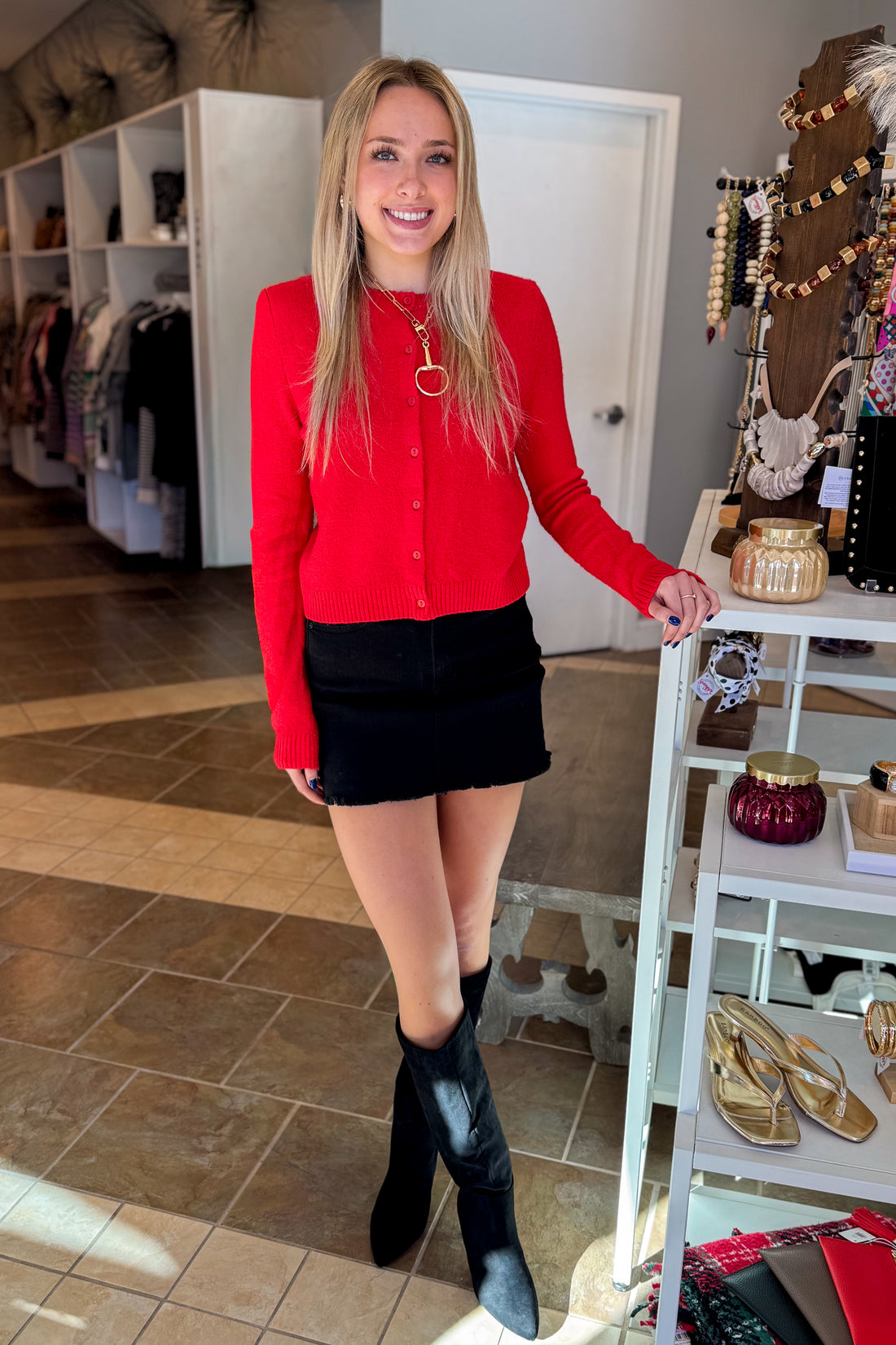 Front view of woman wearing Swagger Boutique’s Red Button Up Cardigan with Black Denim Mini Skirt by Just Black Denim standing at the store.