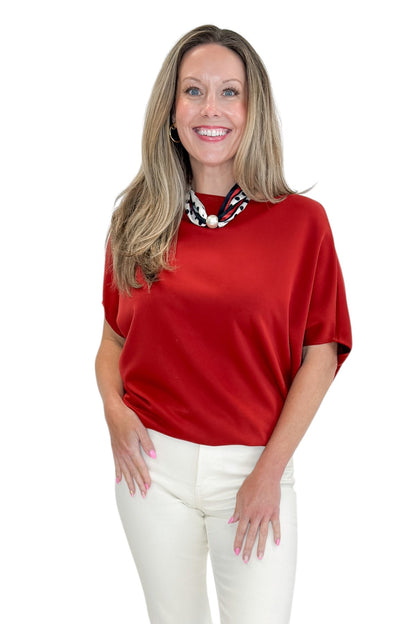 Front view of woman wearing Swagger Boutique’s Red Dolman Sleeve Top with jeans against white studio background.