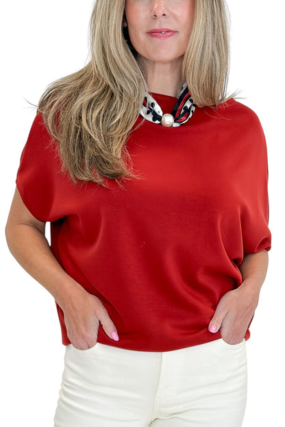 Front detail view of woman wearing Swagger Boutique’s Red Dolman Sleeve Top with jeans against white studio background.