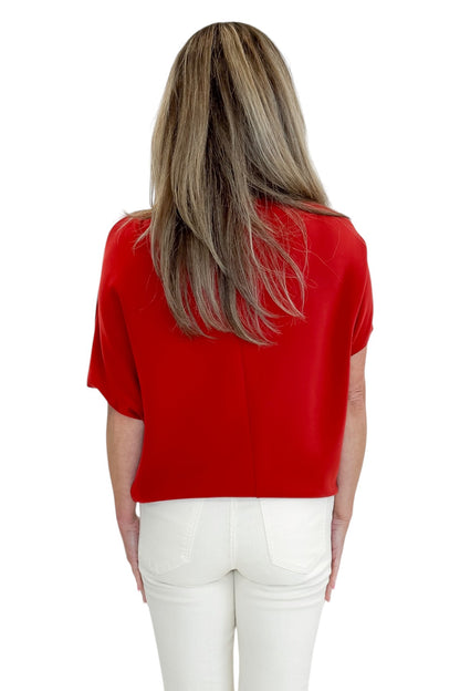 Back view of woman wearing Swagger Boutique’s Red Dolman Sleeve Top with jeans against white studio background.