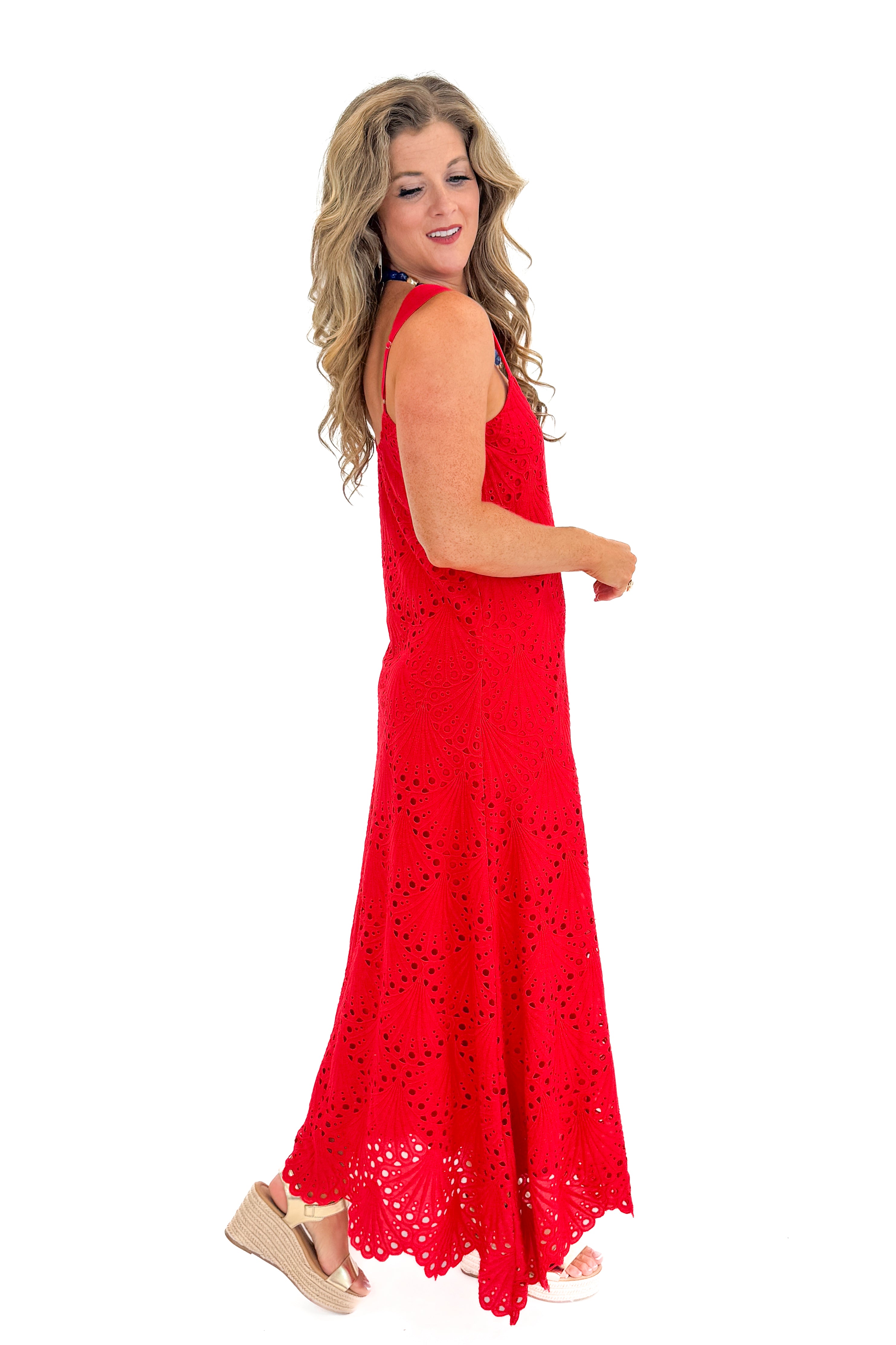 Side view of woman wearing Swagger Boutique’s Red Embroidered Maxi Dress with sandals against white studio background.