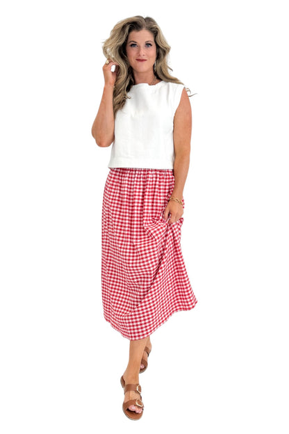 Front view of woman wearing Swagger Boutique’s Red Gingham Flowy Midi Skirt with White Denim Tank against white studio background.