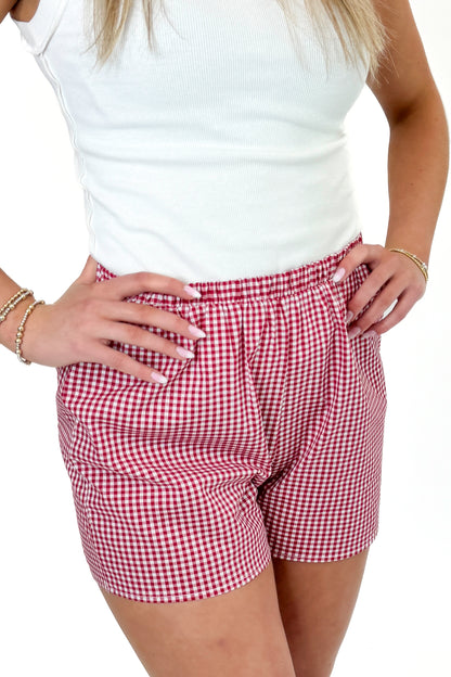 Front detail view of woman wearing Swagger Boutique’s Red Gingham Shorts with Off White Round Hem Ribbed Tank against white studio background.