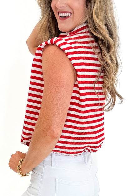 Side detail view of woman wearing Swagger Boutique’s Red Striped Sleeveless High Neck Top with jeans against white studio background.